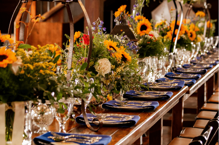 Elegant banquet table set with floral centerpieces, blue napkins, and glassware for a formal event